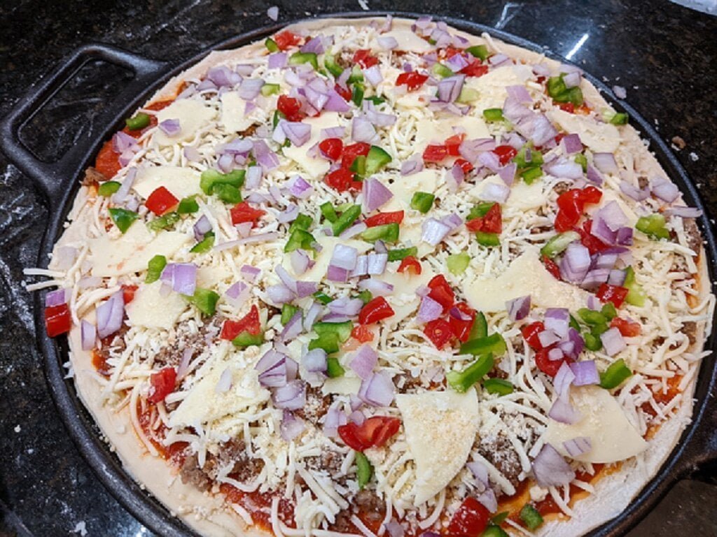 Add veggies to cast iron pizzas