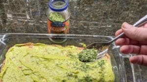 adding cilantro on top of guacamole for 7 layer dip recipe