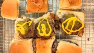 adding classic mustard and pickle slice as toppings to burger sliders recipe