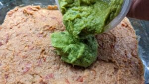 adding layer 2 of guacamole to 7 layer taco dip recipe