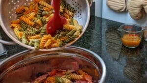 adding pasta into bowl for antipasto tortellini salad