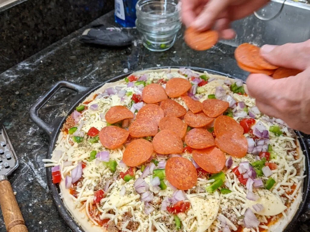 Adding pepperoni as final topping to pizza cast iron pan