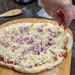 adding pizza toppings to a pepperoni pizza homemade