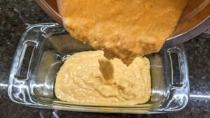 adding recipe for cornbread batter into greased loaf casserole dish