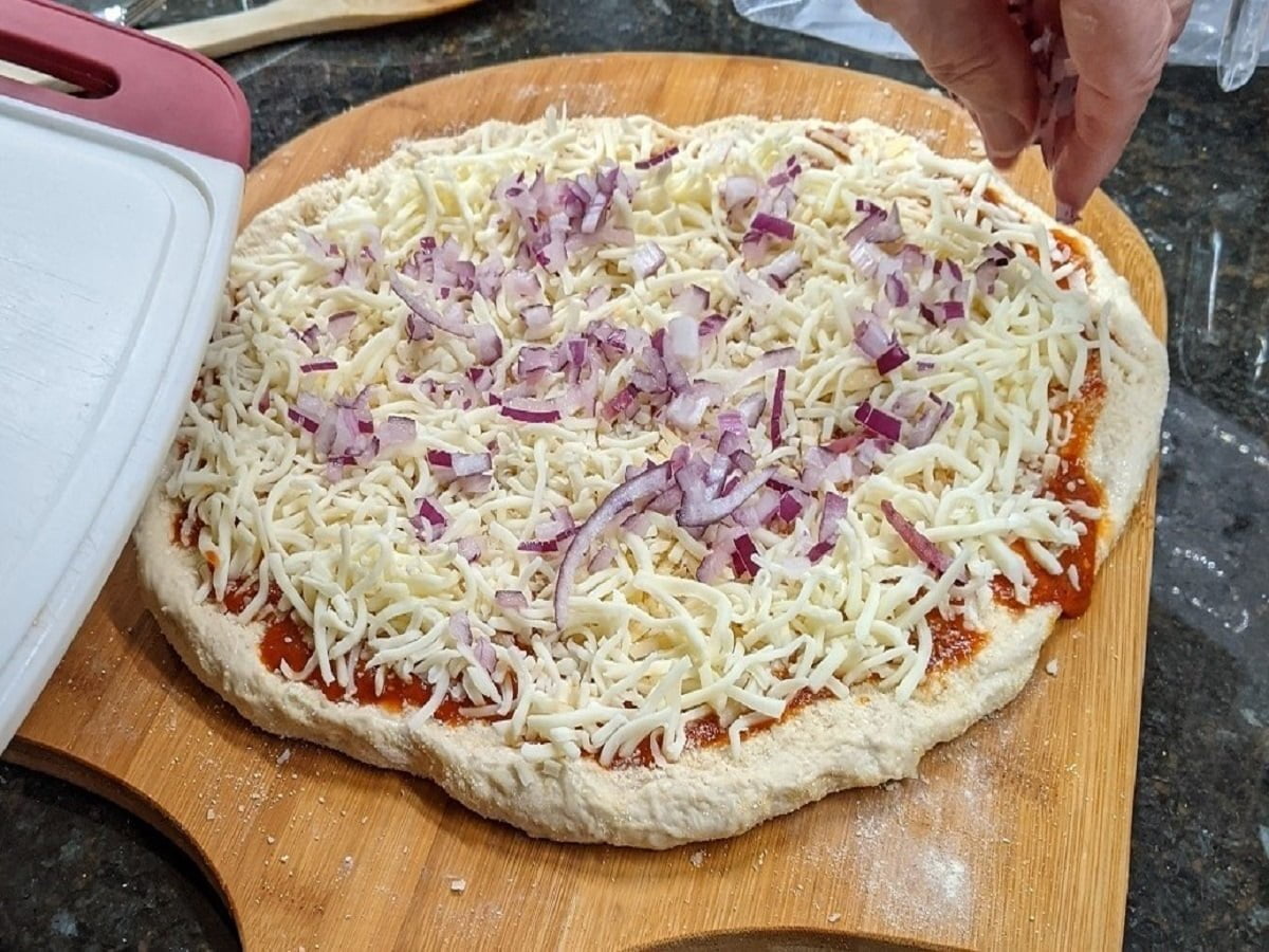 Adding veggie toppings on sausage and pepperoni pizza