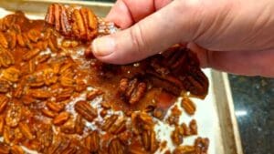 breaking apart individual honey roasted pecans after cooled