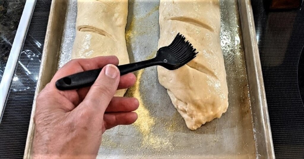 brushing french bread loaves with olive oil