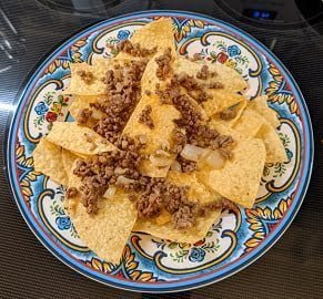 Building ground beef nachos by adding meat