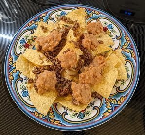 Building ground beef nachos by adding refried beans