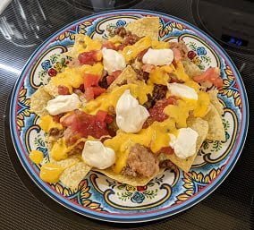 Building ground beef nachos finish by adding sour cream