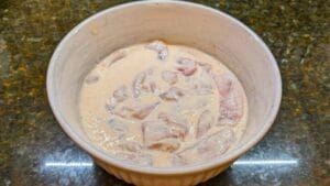 coating chicken in bowl of seasoned buttermilk