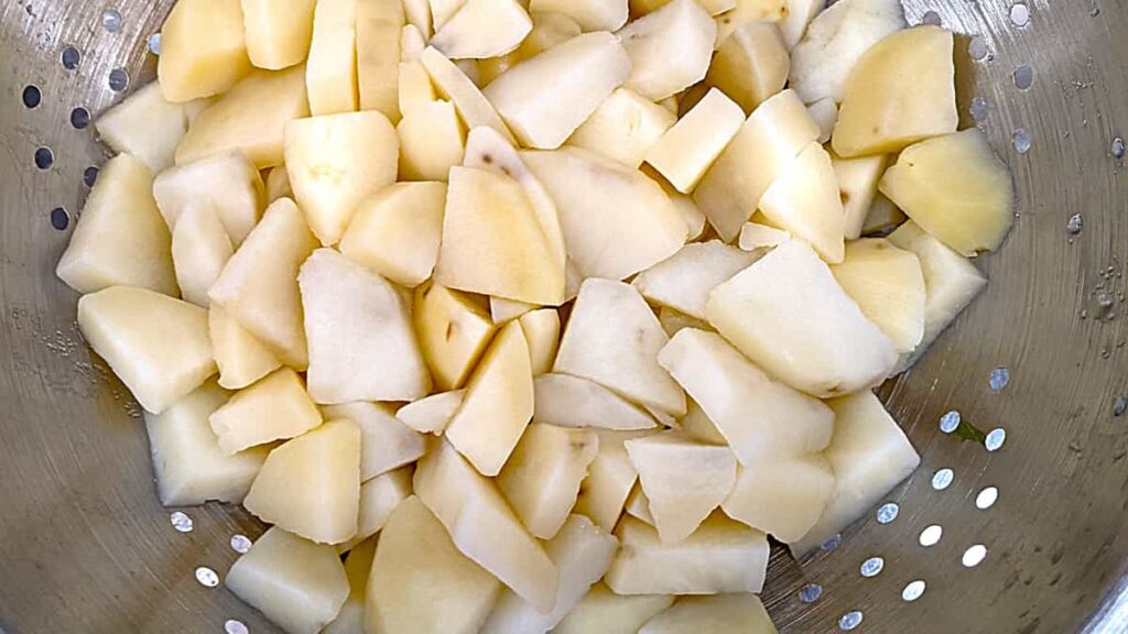 cooked cutup potatoes draining in colander for recipe for southern potato salad