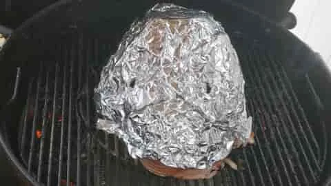 covering the spiral ham on the grill with foil