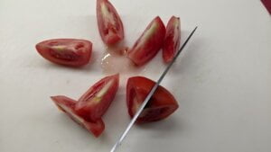 cutting 8 sections of tomato for cucumber tomato salad