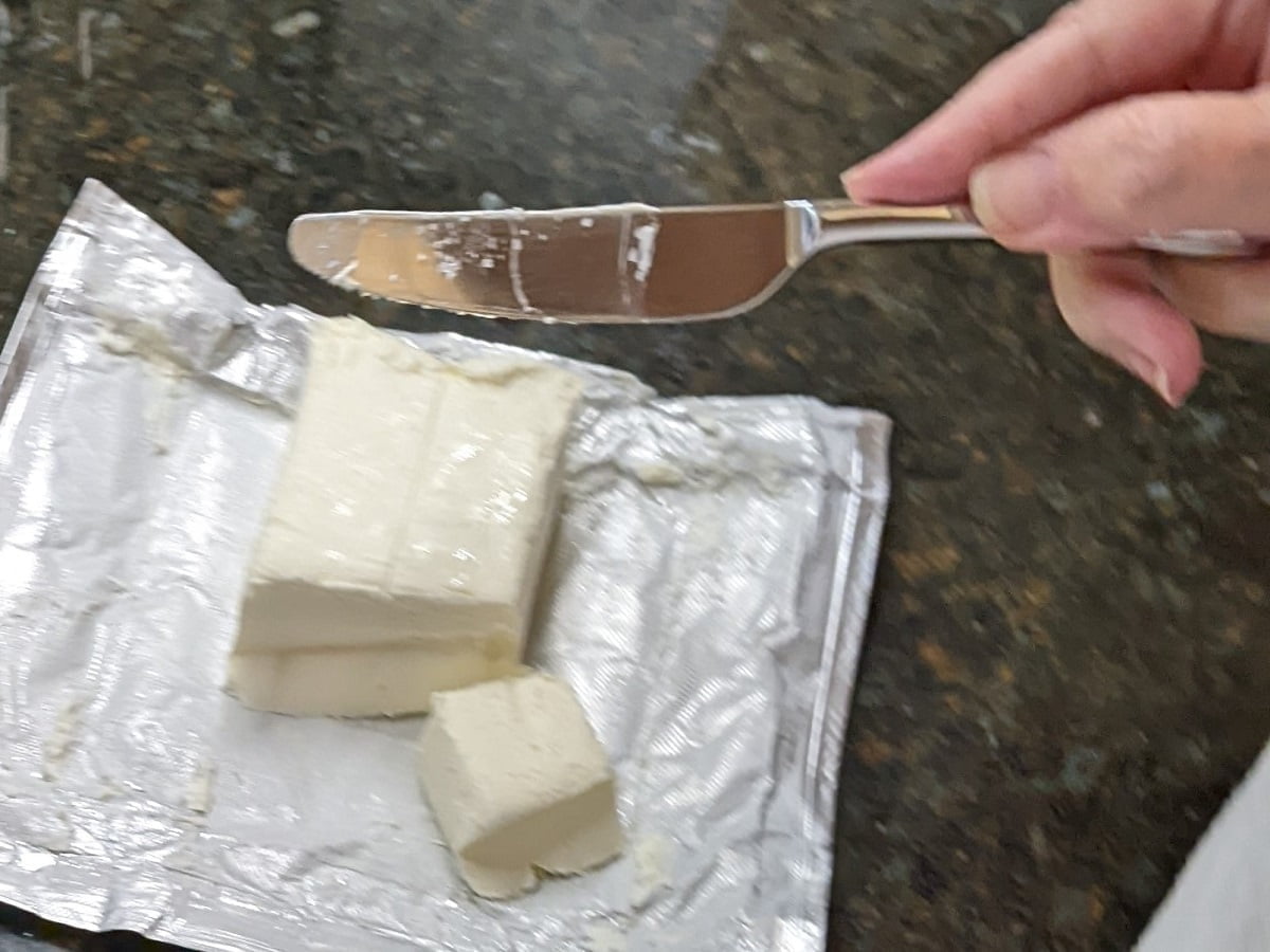 Cutting cream cheese for lime jello salad with pineapple and cream cheese