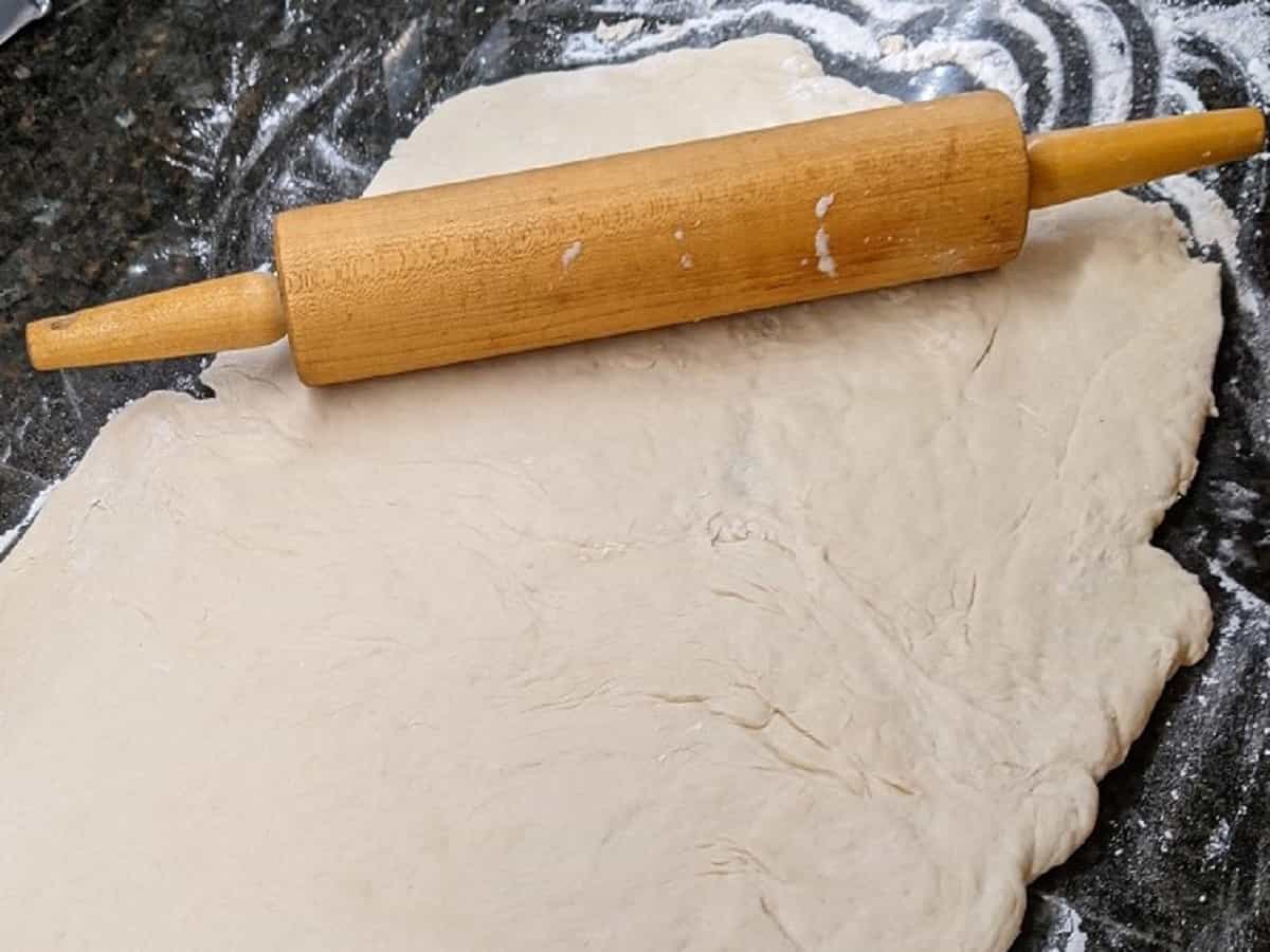 dough being rolled for sausage pepperoni pizza