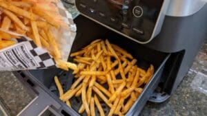 dumping checkers fries into air fryer for guided recipe step