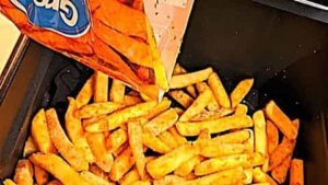 dumping frozen fries into preheated air fryer for recipe