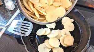 dumping potatoes into skillet for recipe for pan fried potato slices