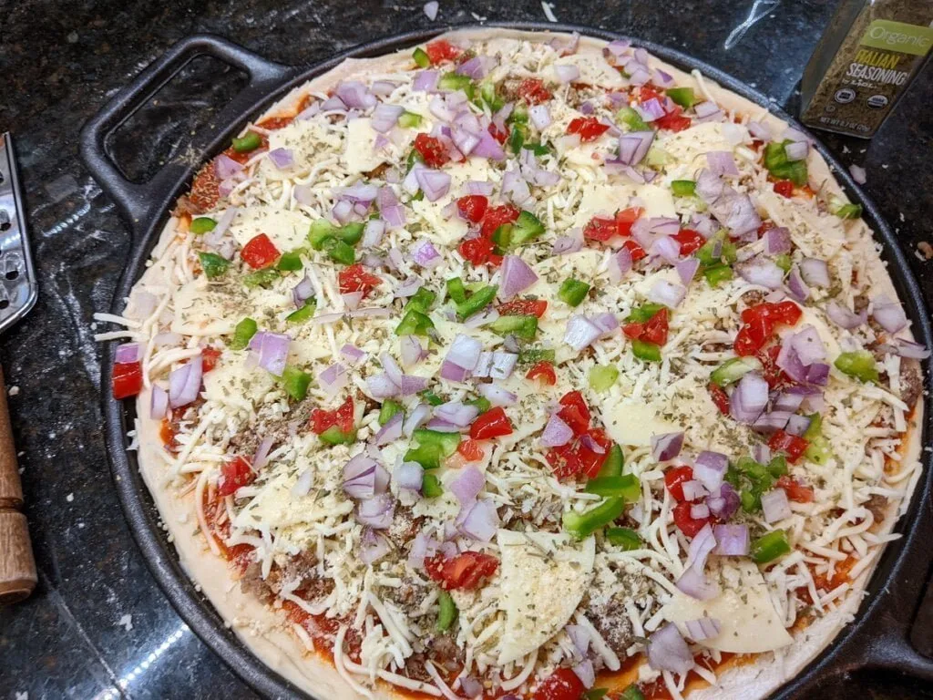 Final veggie toppings added to pizza cast iron pan