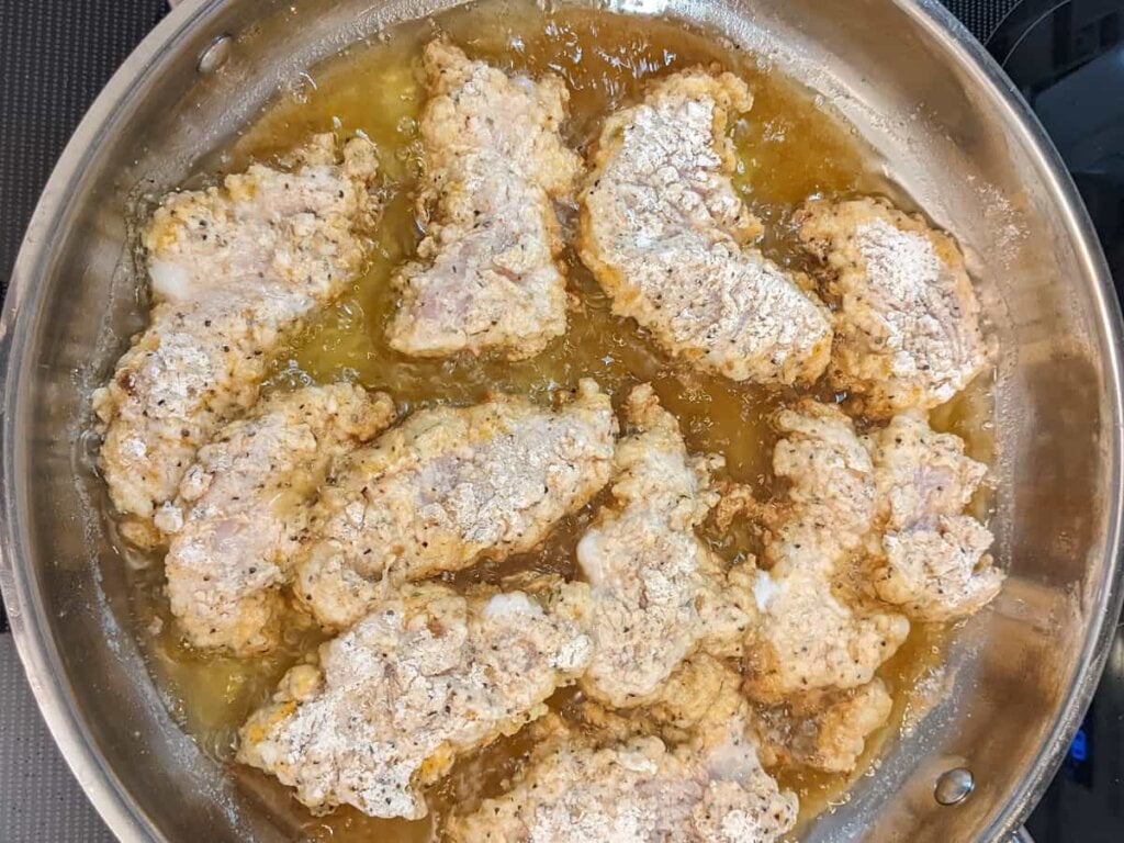 frying chicken strips in skillet for recipe for crispy fried chicken strips