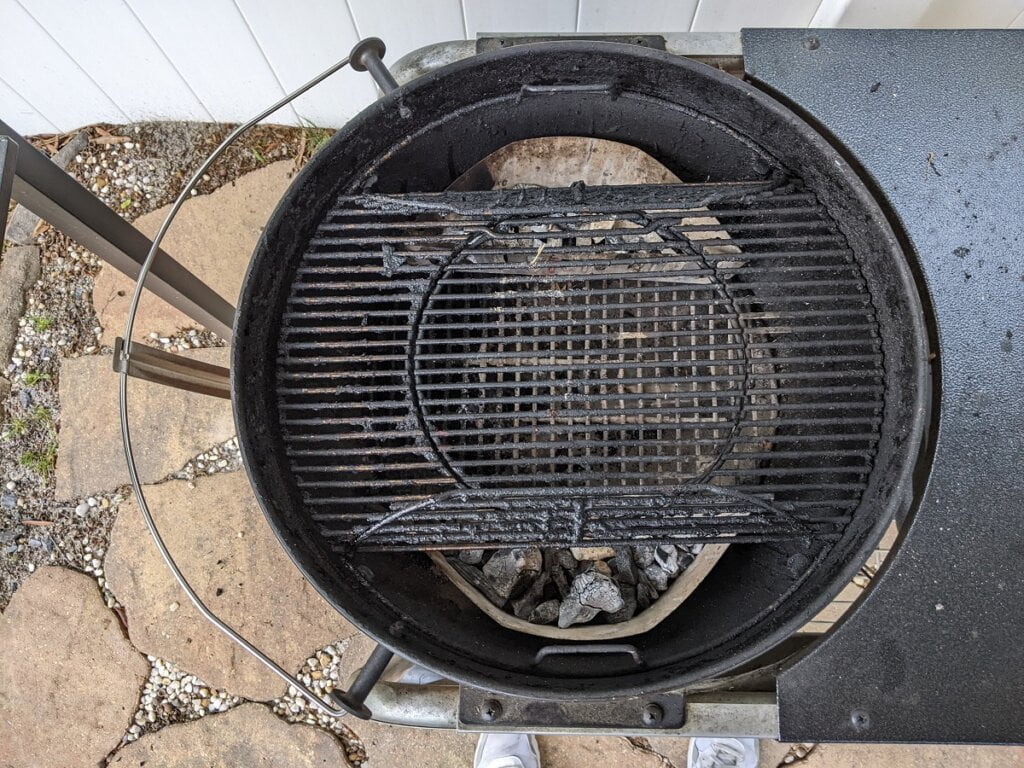 hinged sides of grill grate lifted open for refilling charcoal