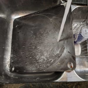 how to clean pizza steel by scraping food off under running water
