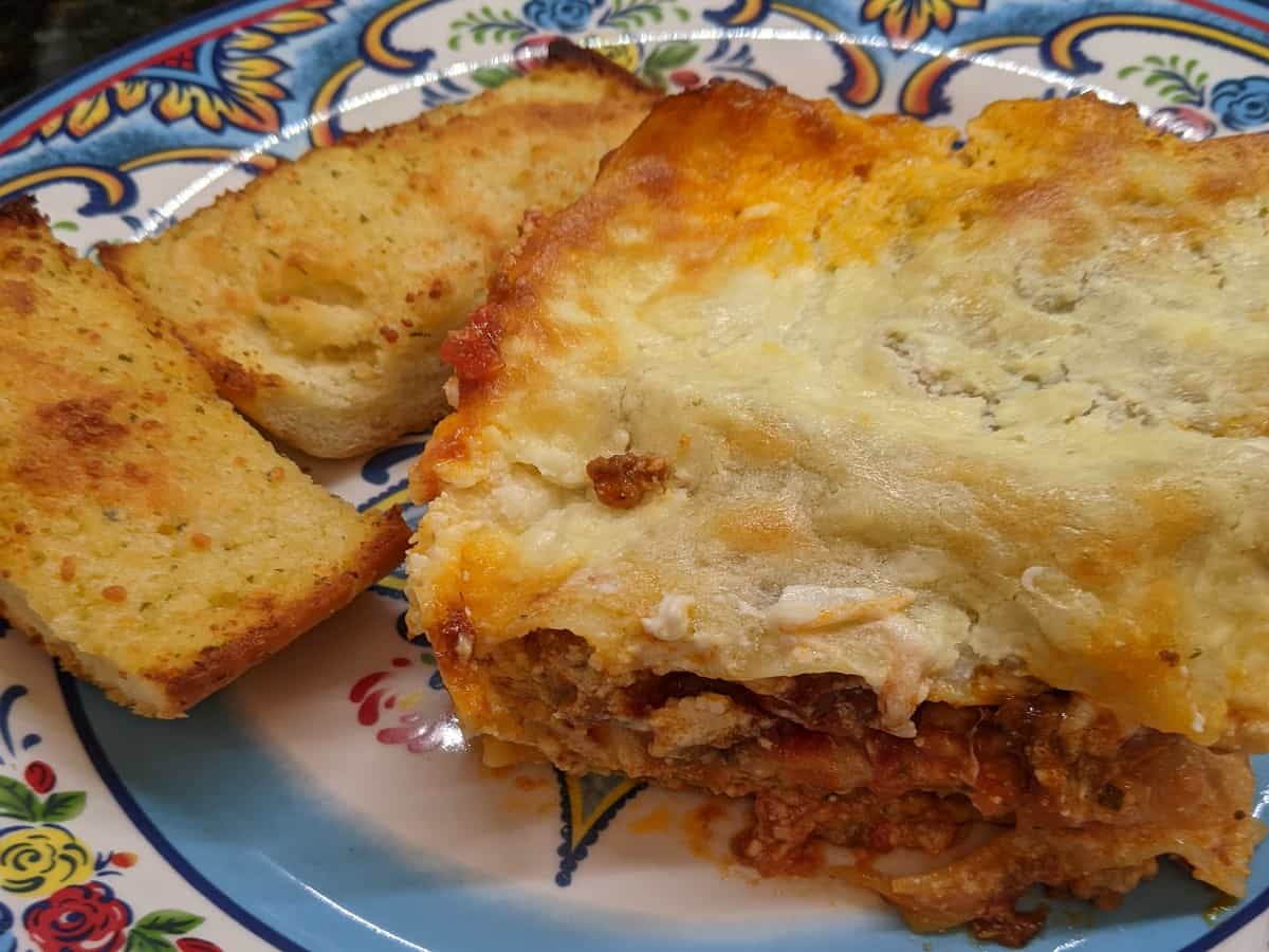 lasagna and garlic bread meal on dinner plate