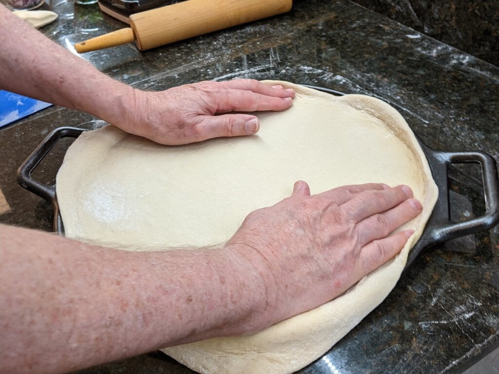 Lay pizza dough onto cast iron pizzas surface