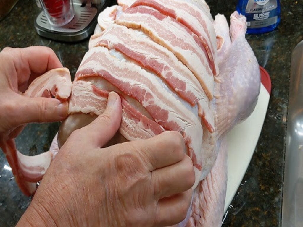 laying bacon strips across turkey