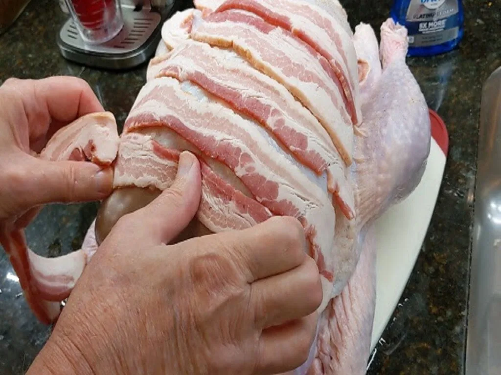 laying bacon strips over the turkey