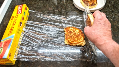 lifting covered 1st pancake over to cover top of 2nd pancake for plastic wrap storing