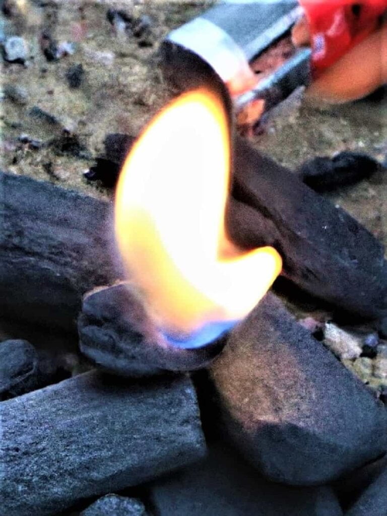 Lighting charcoal with lighter fluid for grilling on charcoal