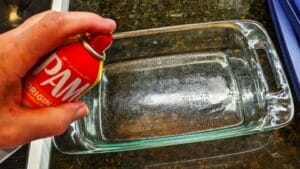 spraying pam on a casserole dish to prep for canned baked beans in oven