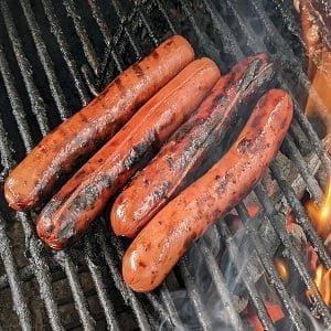 Managing hot dogs on a grill alongside burgers