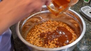 Mixing bowl with ingredients for a baked beans casserole using canned beans