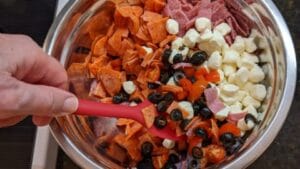 mixing up prepped meats veggies cheese for antipasto tortellini salad recipe