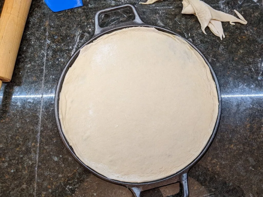 Pizza dough ready on pizza cast iron pan