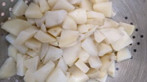 Potato pieces peeled in colander for potatoes and green beans