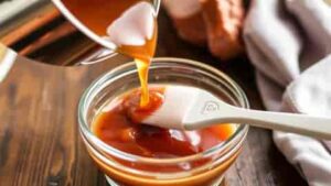 pouring cooked mustard and honey glaze into basting container for honey dijon glaze for ham recipe