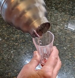 pouring shaken cranberry vanilla vodka into flute