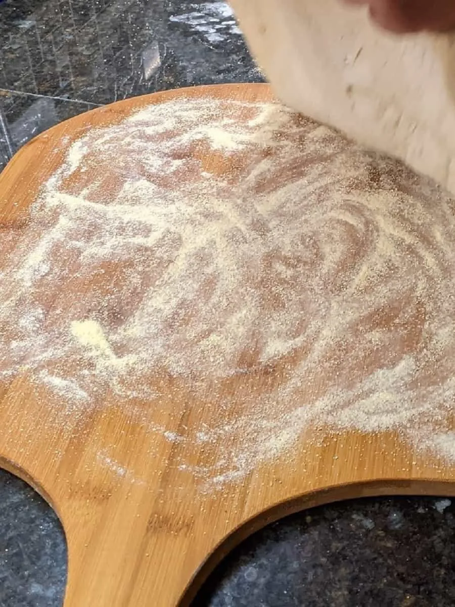 prepared wooden pizza peel with cornmeal ready for pizza dough