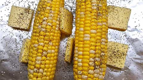prepping just before wrapping up corn on the cob in the oven in foil