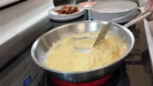 pulling egg mixture from sides to let raw eggs flow into place for scrambled eggs recipe