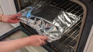 putting foil tent covered burger sliders in oven for steaming step of recipe