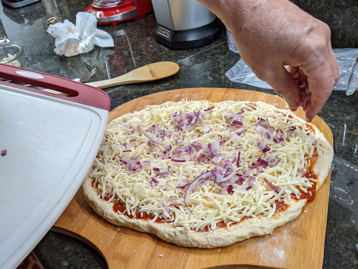 Putting toppings on sausage pepperoni pizza