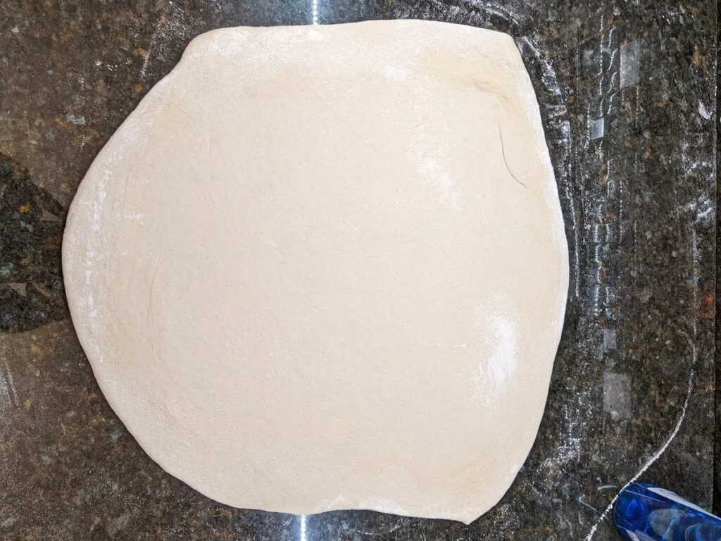 Roll out pizza dough to estimated size for pizza cast iron pan