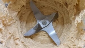 scrape creamy hummus mixture from hummus blender into bowl