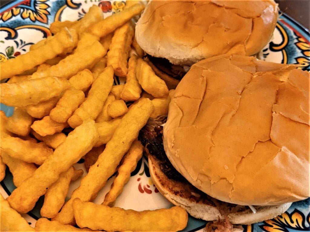 serving pulled pork sandwich with side of french fries