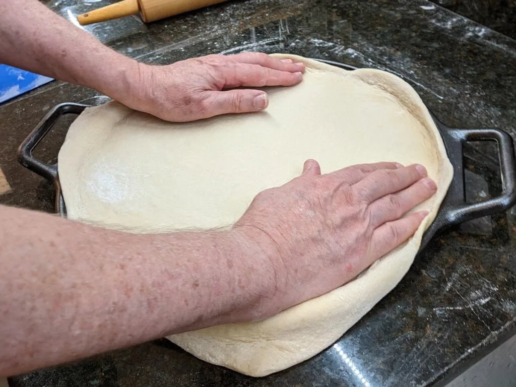 Shape trim and stretch dough to fit into pizza cast iron pan